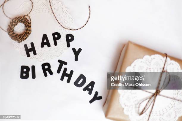 gift wrapped in brown paper, doily and string, beside letters spelling happy birthday - virkad duk bildbanksfoton och bilder