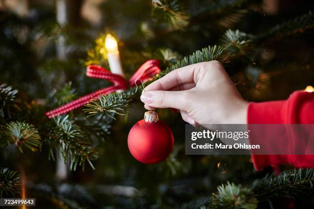 young woman hanging bauble on christmas tree, close-up - christmas tree close up stock pictures, royalty-free photos & images