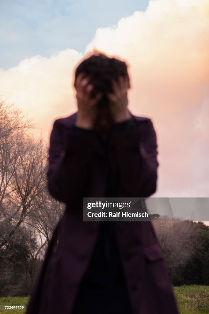 Depressed woman standing against sky during sunset