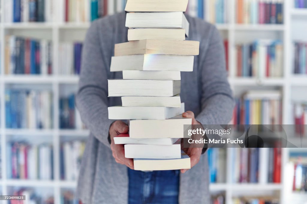 Woman holding stack of books, mid section