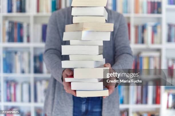 woman holding stack of books, mid section - books stack stockfoto's en -beelden