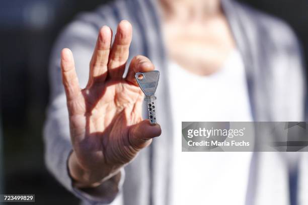 senior woman holding security key, mid section - key stock-fotos und bilder