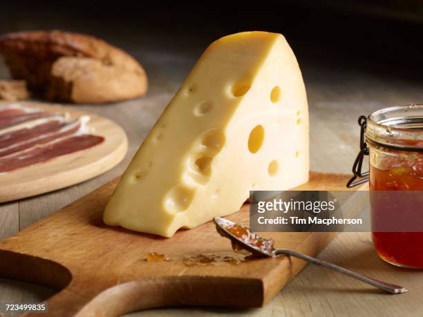 still life of edam cheese with quince chutney, on chopping board - edamer stock-fotos und bilder