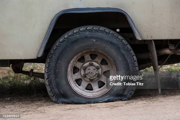 close-up of vehicle with flat tire on field - deflated stock-fotos und bilder