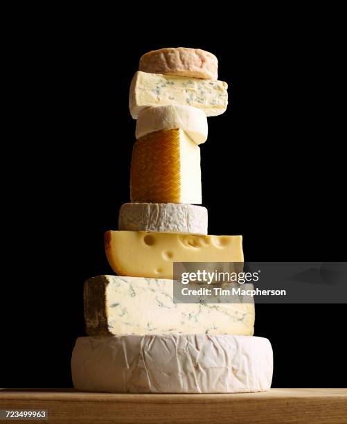 stack of selection of cheeses, against black background - wiel kaas stockfoto's en -beelden