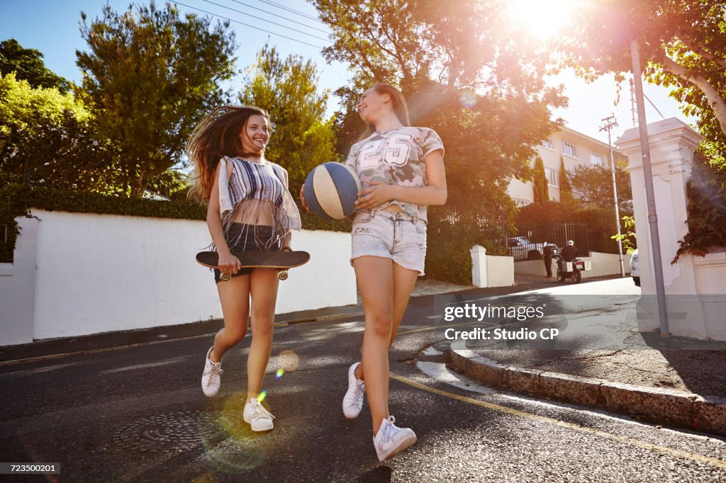 Teenage girls with ball and skateboard in street, Cape Town, South Africa