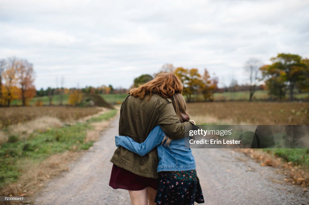 Mother and daughter hugging on dirt road, Lakefield, Ontario, Canada