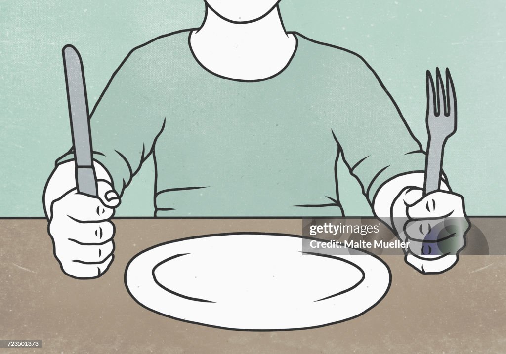 Midsection of man holding fork and knife at table