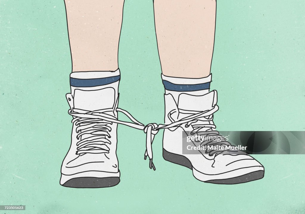 Low section of man with shoelaces tied together against colored background