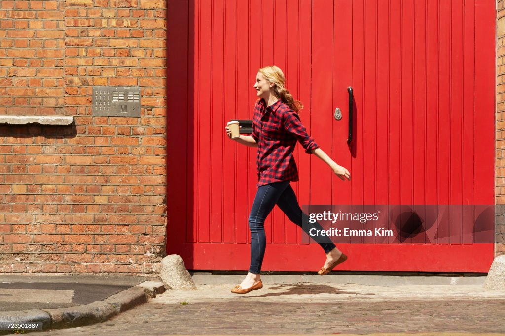 Woman walking past red door, London, UK