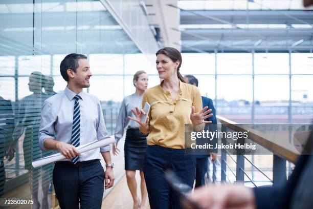 businesswoman and men walking and talking on office balcony - businesswoman in suit jackets stock-fotos und bilder