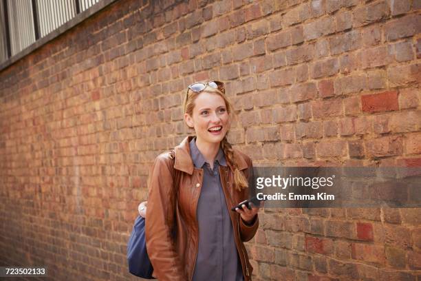 woman walking along brick wall, london, uk - portare sulla testa foto e immagini stock