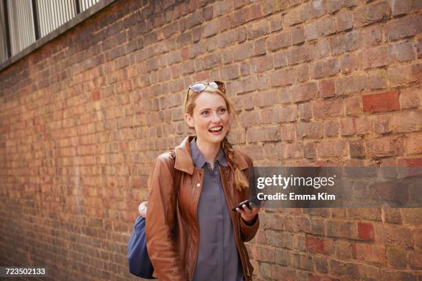 woman walking along brick wall, london, uk - carrying on head stockfoto's en -beelden