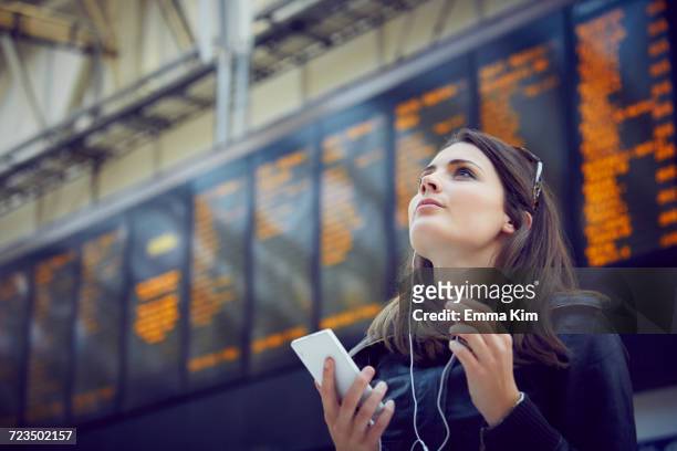 woman looking at departure information, london, uk - station stock-fotos und bilder