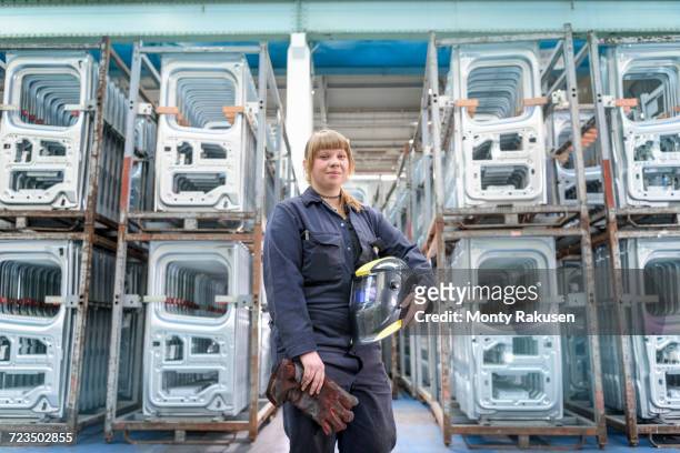 female apprentice welder holding equipment in car factory, portrait - automobile industry stock pictures, royalty-free photos & images