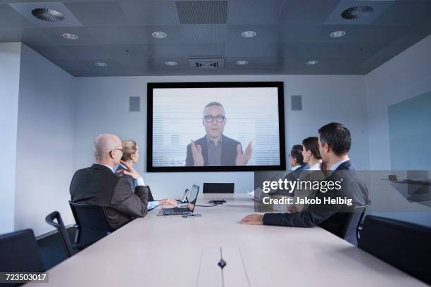 businessmen and women watching office conference call - conference room screens stock pictures, royalty-free photos & images