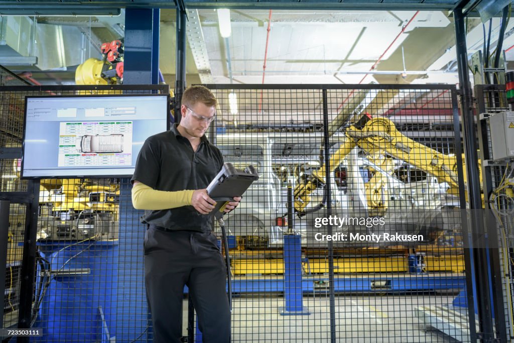 Apprentice Engineer Operating Robots On Production Line In Car Factory ...