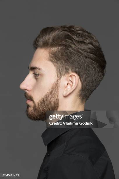 side view of young man looking away against gray background - 横顔　男性 ストックフォトと画像