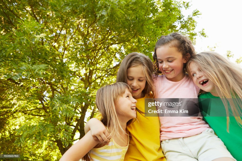 Four girls with arms around each other in park