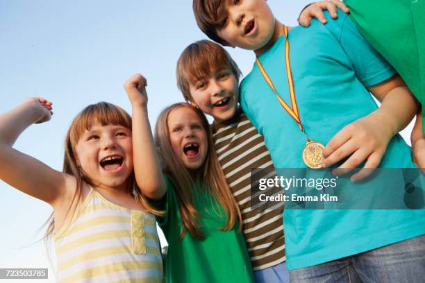 boy with gold medal and team cheering against blue sky - emma awards stockfoto's en -beelden