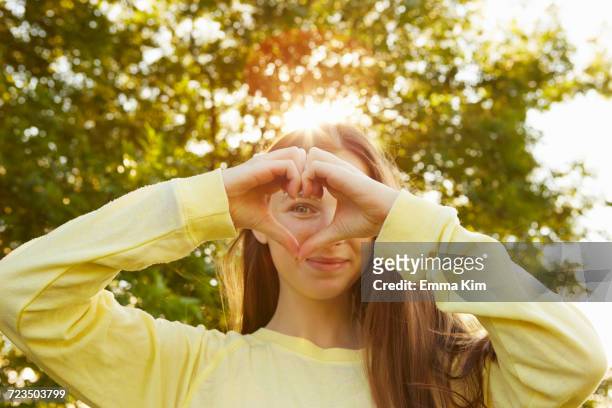 portrait of girl making heart shape with hands in park - angelica hale fotografías e imágenes de stock
