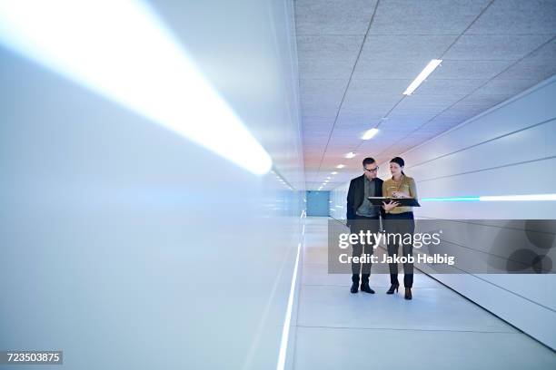 businesswoman and man reading file in office corridor - perspektive stock-fotos und bilder