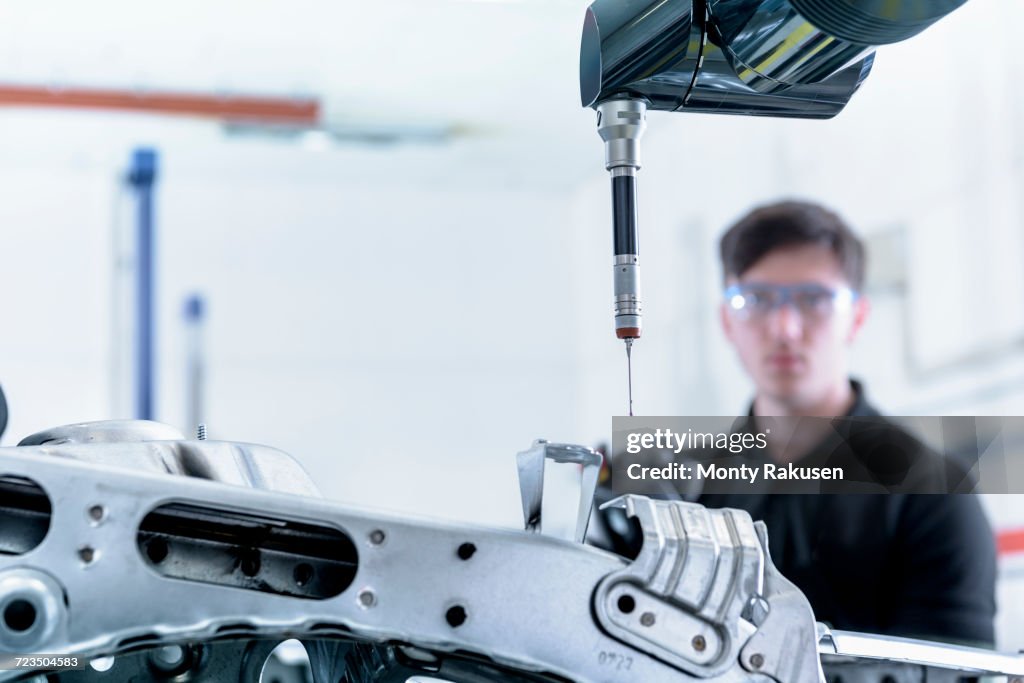 Apprentice engineer measuring car body in car factory