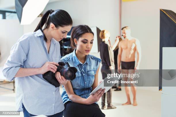 fashion model and photographer reviewing shoot on digital tablet in photography studio - fashion photographer stock pictures, royalty-free photos & images