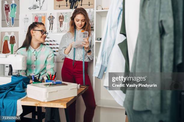 Happy designer looking at female trainee holding container at design studio