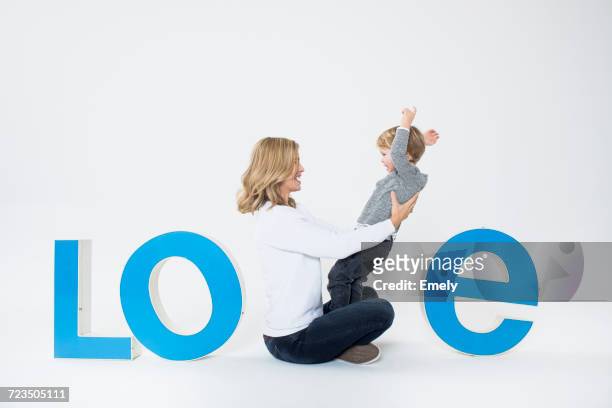 mother and son sitting between three-dimensional letters, creating the word love - love letter 個照片及圖片檔