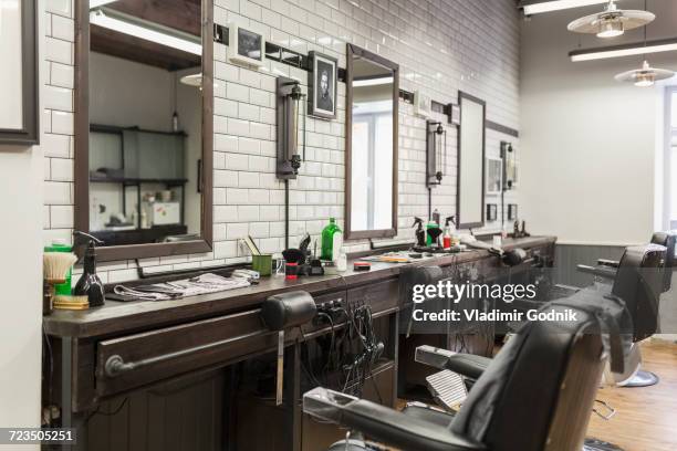 empty chairs in front of mirrors at barber shop - barbiere foto e immagini stock
