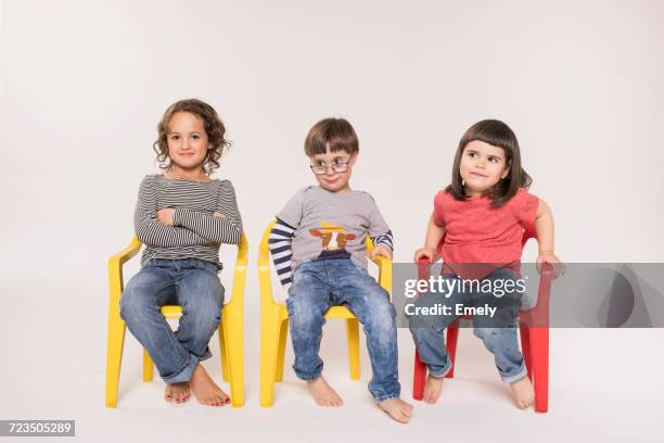 portrait of three children sitting in colourful chairs, studio shot - chairs in a row stock pictures, royalty-free photos & images