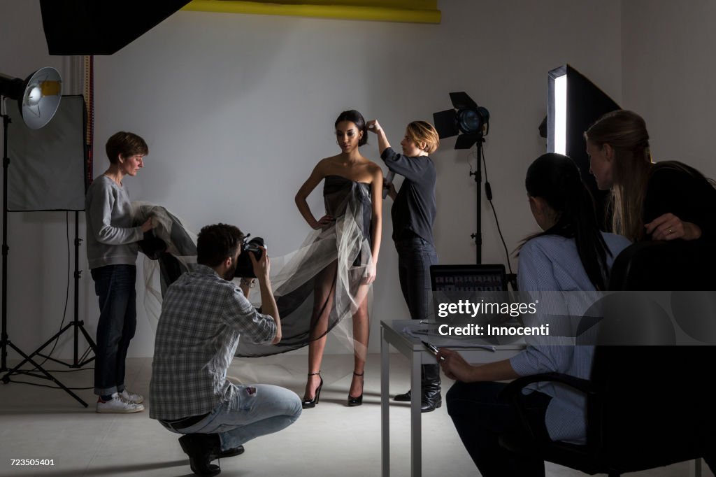 Stylists styling model in low key photography studio shoot