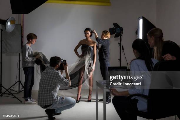 stylists styling model in low key photography studio shoot - sessão fotográfica imagens e fotografias de stock