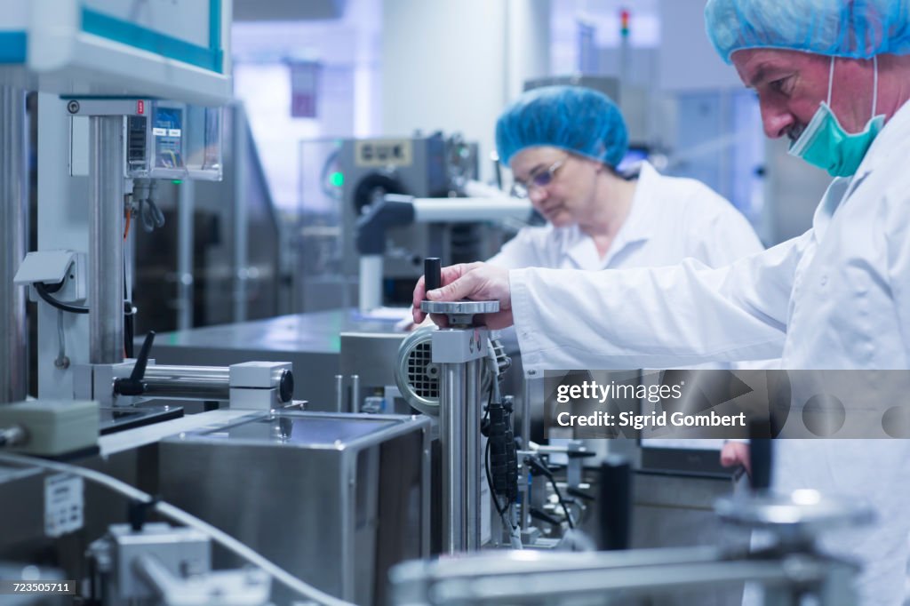 Workers operating machinery in pharmaceutical plant