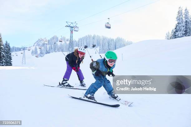 teenage girl and brother skiing down ski slope, gstaad, switzerland - sport d'hiver photos et images de collection