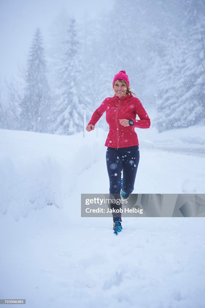 Female runner running in falling snow, Gstaad, Switzerland