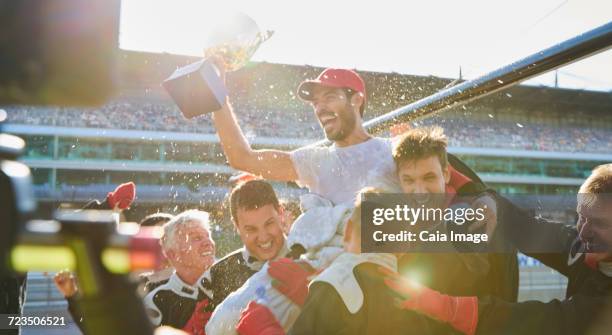 open-wheel single-seater racing car racing team carrying driver with trophy on shoulders, celebrating victory - spraying champagne stock pictures, royalty-free photos & images