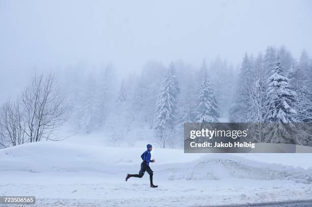 distant view of male runner running in deep snow, gstaad, switzerland - bern stock-fotos und bilder