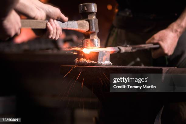 farriers forging horseshoe on anvil - smederij stockfoto's en -beelden