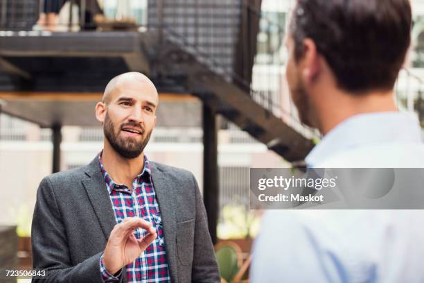 confident businessman discussing with male colleague at office yard - formal garden fotografías e imágenes de stock