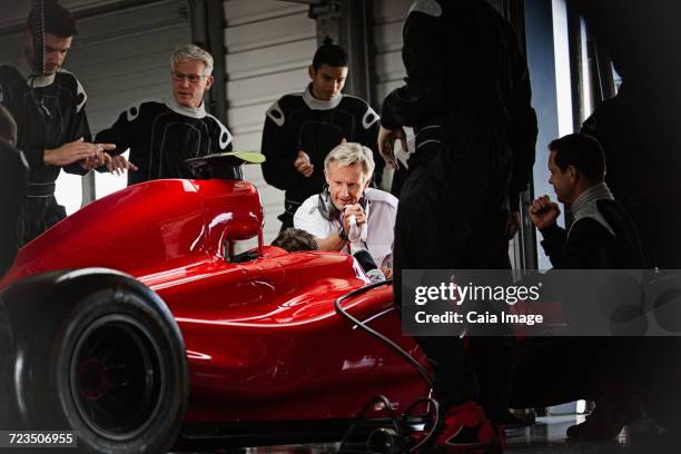 manager and pit crew working on open-wheel single-seater racing car race car in dark repair garage - race ethnicity stock pictures, royalty-free photos & images