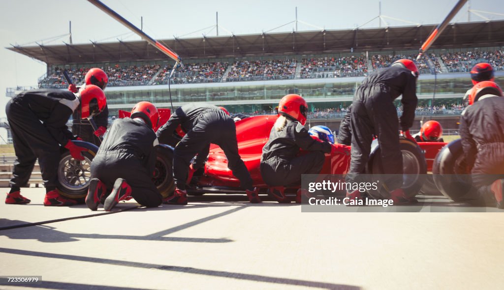 Pit crew replacing tires on open-wheel single-seater racing car race car in pit lane