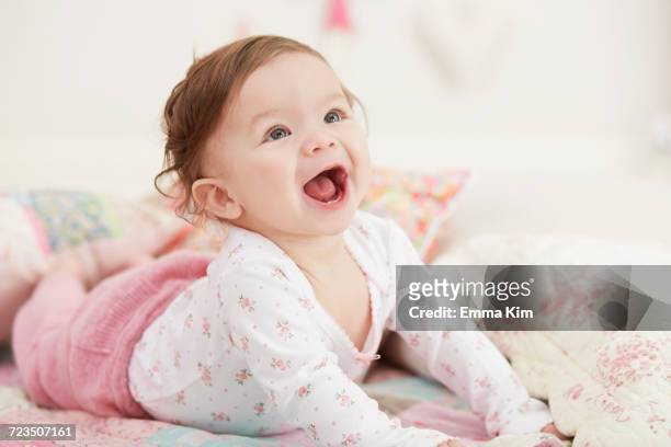 portrait of baby girl, lying on her front, laughing - baby girls stock pictures, royalty-free photos & images