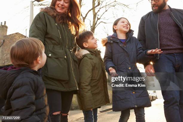 mid adult couple and three children strolling on street - parka coat stock-fotos und bilder