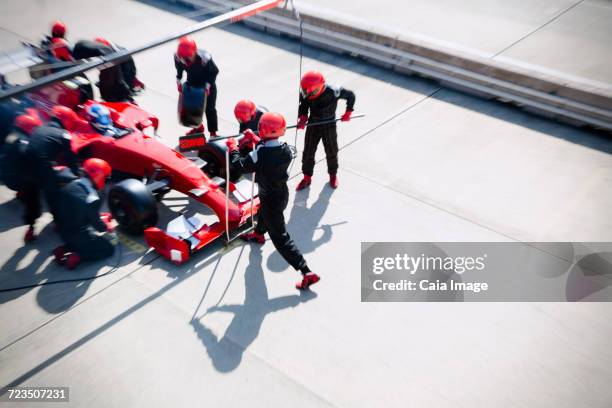 pit crew replacing tires on open-wheel single-seater racing car race car in pit lane - car racing blurred motion stock pictures, royalty-free photos & images