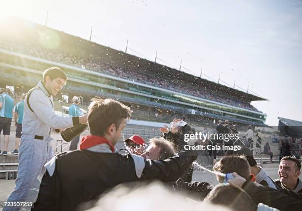 formula one racing team and driver spraying champagne, celebrating victory on sports track - car racing stadium stock pictures, royalty-free photos & images