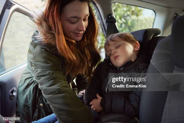 mother removing sleeping toddler son from car backseat - parka stock pictures, royalty-free photos & images