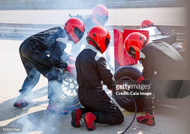 pit crew replacing tires on open-wheel single-seater racing car race car in pit lane - autorennen stock-fotos und bilder