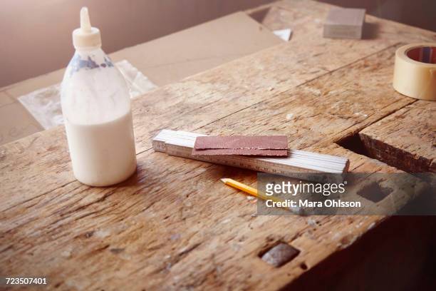 carpenters workbench with glue, sandpaper and tape measure - trestles stock-fotos und bilder